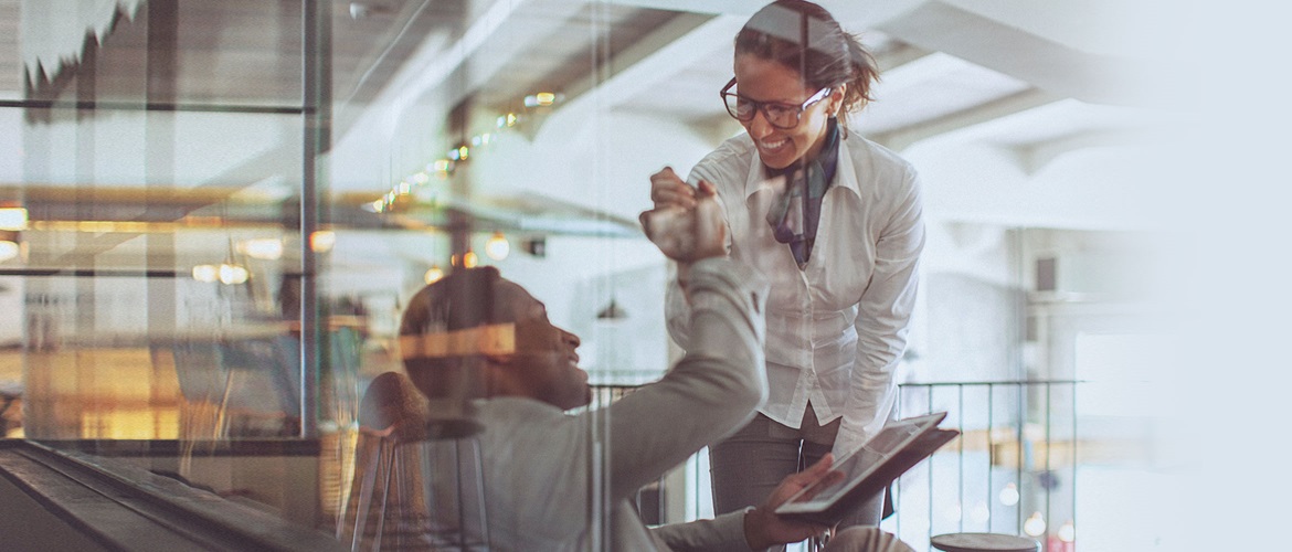 Man and woman high fiving and smiling in office setting