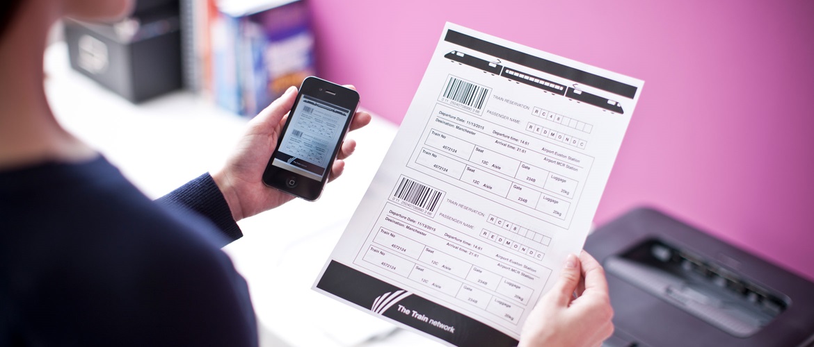 Woman checking printed page next to her mobile screen